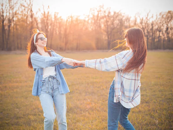 两名年轻女子日落时在秋天的田野上跳舞 — 图库照片