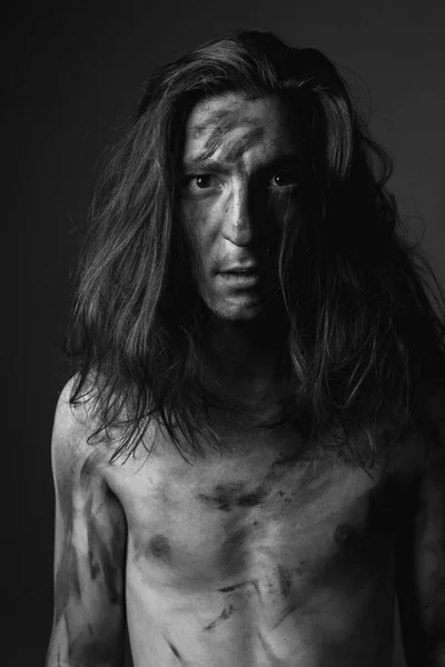 Portrait of young man with long hair in soot. Black and white