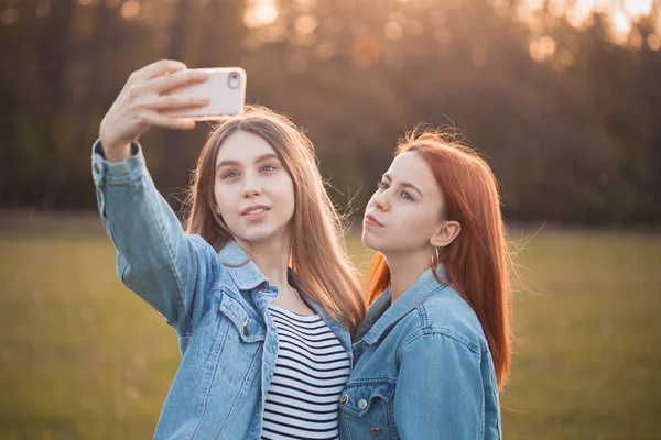 Two young women shooting selfie on the field. Best friends