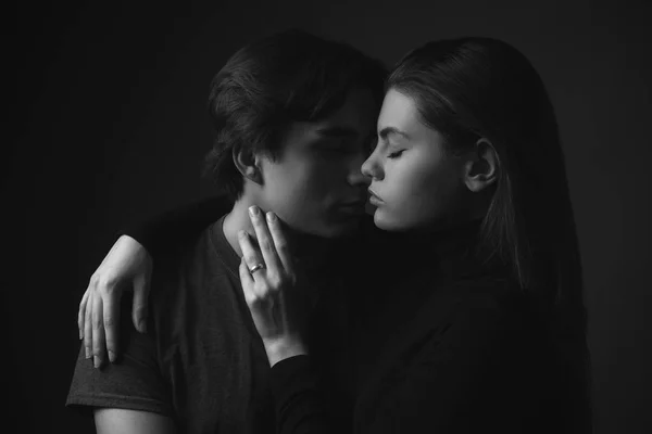 Young man and woman kissing in studio. Black and white