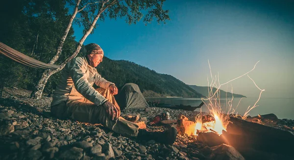 Man near fire on Lake Baikal. Siberia.