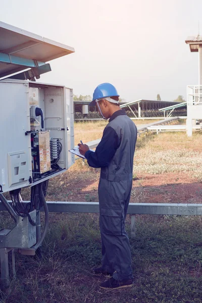 engineer or electrician working on checking and maintenance equipment at green energy solar power plant: checking status inverter