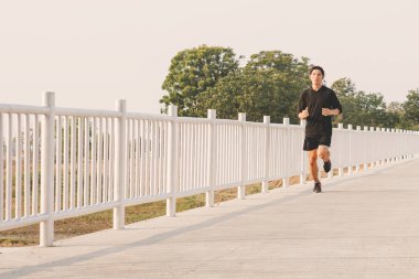 şehir parkında koşu yolu üzerinde çalışan genç adam Runner