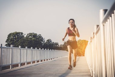 şehir parkında koşu yolu üzerinde çalışan genç kadın Runner