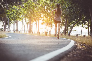 şehir parkında koşu yolu üzerinde çalışan genç kadın Runner