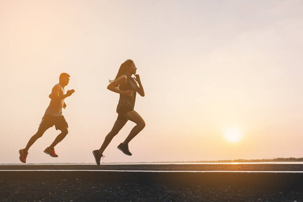 young couple runner running on running road in city park