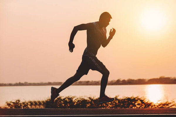 young man runner running on running road in city park