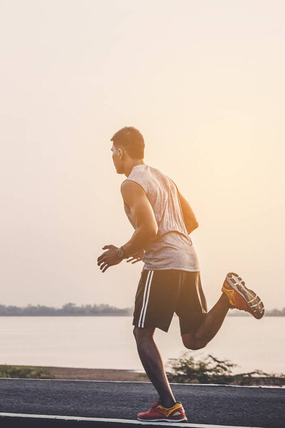 young man runner running on running road in city park