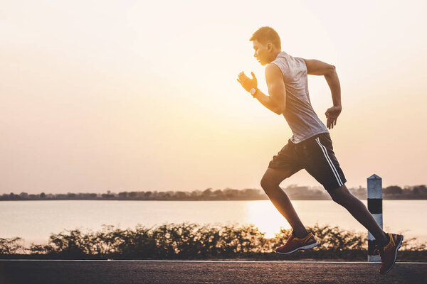 young man runner running on running road in city park