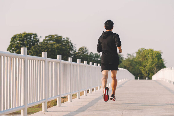 young man runner running on running road in city park
