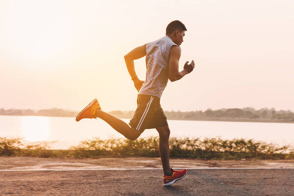 young man runner running on running road in city park