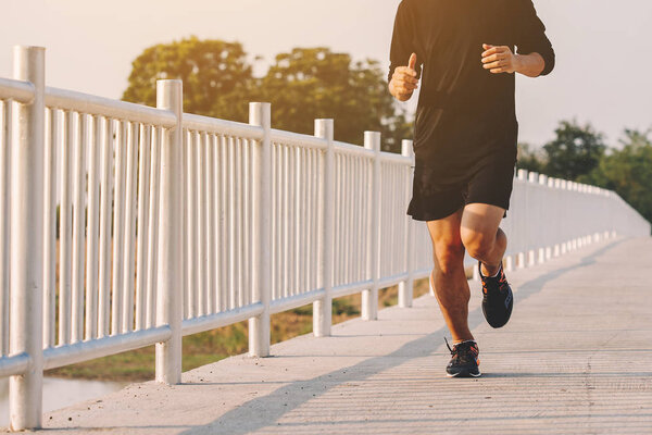young man runner running on running road in city park