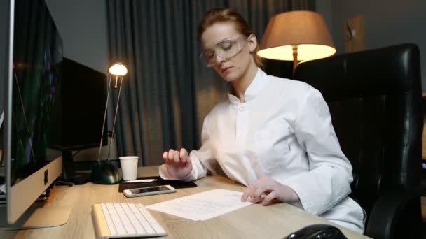 Femme scientifique lit les documents et tape le message au téléphone pendant qu'elle travaille au bureau . — Video