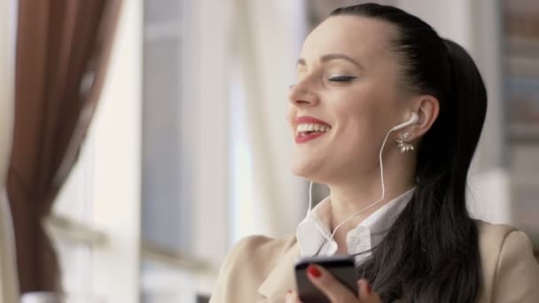 Mulher de negócios em fones de ouvido dançando e cantando uma música no centro de negócios — Vídeo de Stock