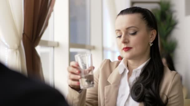 Junge Frau benutzt Smartphone und trinkt Wasser in Café in der Stadt — Stockvideo