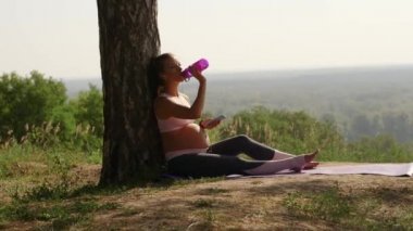 hamile kadın suyu şişeden içer.