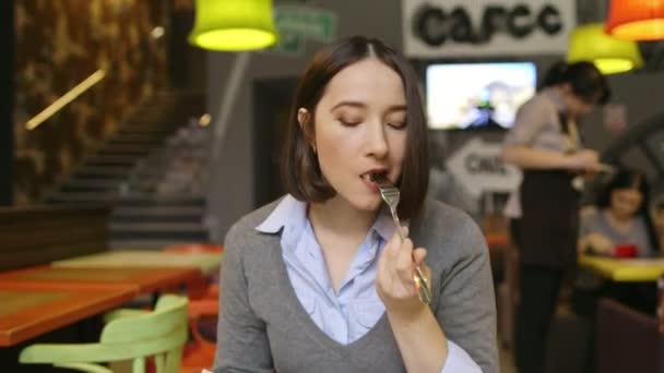 Vrouw eten salade in een overdekt café, close-up op een plaat. — Stockvideo