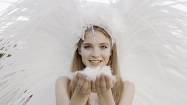 Une femme soufflant des plumes dans ses mains. Plumes et vers le bas dans la direction de la caméra — Video