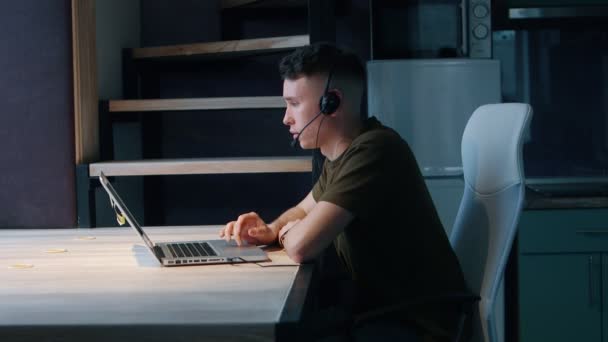 Le jeune homme communique avec le client, répond à l'appel. Concept de bureau à domicile. Vue latérale . — Video