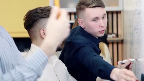 Brainstorming dans le bureau. Des collègues discutent du problème et prennent des notes sur un tableau blanc . — Video