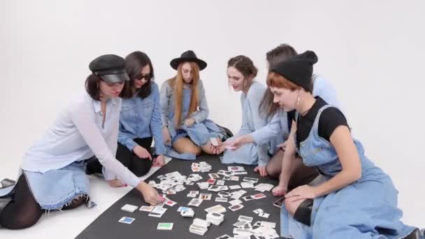 Een groep vrouwen is zittend op de vloer. Vrouwen kiezen voor de stijl van kleding in de foto 's. — Stockvideo