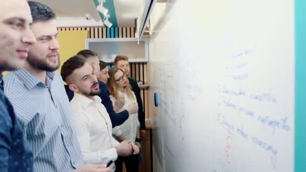 Brainstorming på kontoret. Kollegor diskutera problemet och göra anteckningar på en vit tavla. — Stockvideo