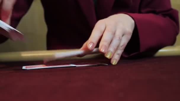 カジノ: ディーラー女性は、テーブルの上の火かき棒のカードを切り直します。手のクローズ アップ。カジノ ギャンブル. — ストック動画