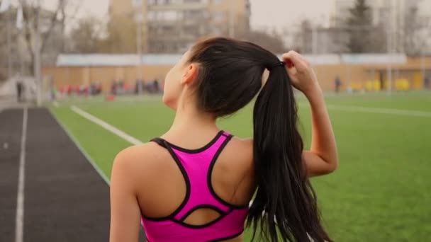 Fiatal sportos ázsiai lány sétál a stadionban, edzés után, és lehetővé teszi, hogy a haja. — Stock videók