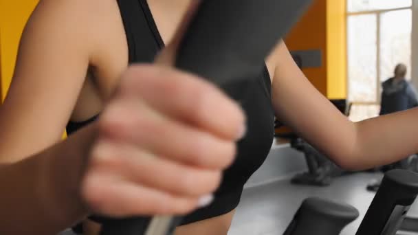 Young asian girl doing sports on the elliptical trainer in gym. — Stock Video