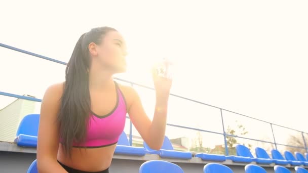 Giovane atleta asiatico ragazza sta riposando seduto allo stadio in una giornata di sole . — Video Stock