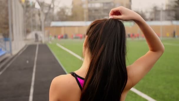 Fiatal sportos ázsiai lány sétál a stadionban, edzés után, és lehetővé teszi, hogy a haja. — Stock videók