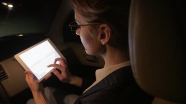 İşkadını arabada bir tablet iş için kullanır. Gece yolda arabaya biniyor.