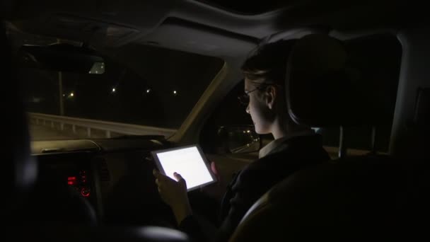 Empresaria en el coche utiliza una tableta para el trabajo. Viaja en el coche por la carretera nocturna. . — Vídeos de Stock