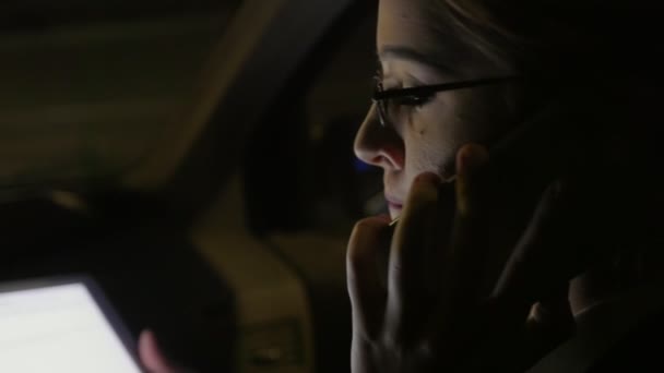Kobieta w samochodzie rozmawia przez telefon. Jeździ w samochodzie na drodze noc. — Wideo stockowe