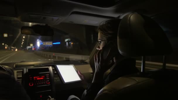 Zakenvrouw in de auto praten aan de telefoon. Ze rijdt in de auto op de weg van de nacht. — Stockvideo