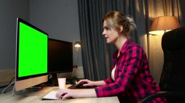 Kadın bilgisayarında çalışıyor, ofiste çalışıyor. Monitör yeşil ekran, yan görünüm.