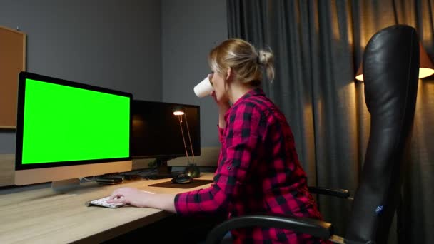 Una donna lavora al computer, lavora in ufficio. Monitora schermo verde, vista laterale . — Video Stock