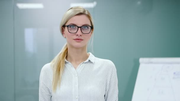 Young blonde businesswoman in office clothes and glasses is looking at camera and smiling. — Stock Video