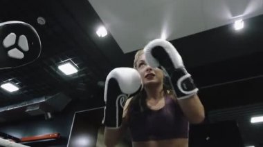 Kadın kickboks antrenmanı yapıyor. Spor salonunda eldiven kullanarak yumruk atma alıştırması yapıyor..