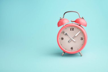 Çalar saat. Saatçi yerine çatal ve bıçak. Perhiz, öğle yemeği, diyet ve kilo kaybı kavramı