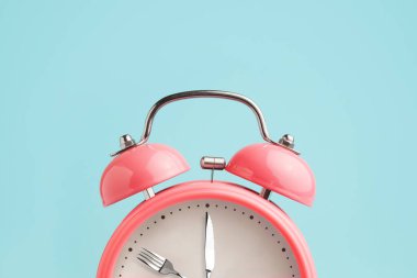 Çalar saat. Saatçi yerine çatal ve bıçak. Perhiz, öğle yemeği, diyet ve kilo kaybı kavramı