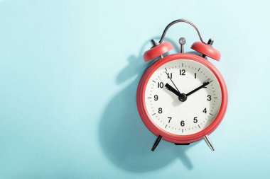 Mavi arka planda duran kırmızı alarmlı saat. Yukarıdan görüntüle.