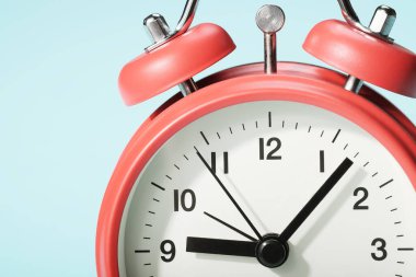 Mavi zemin üzerinde kırmızı alarm saati var. Dokuza yedi var..