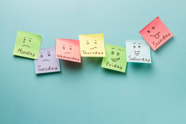 Day of week and face expression. Colored stickers on a blue background