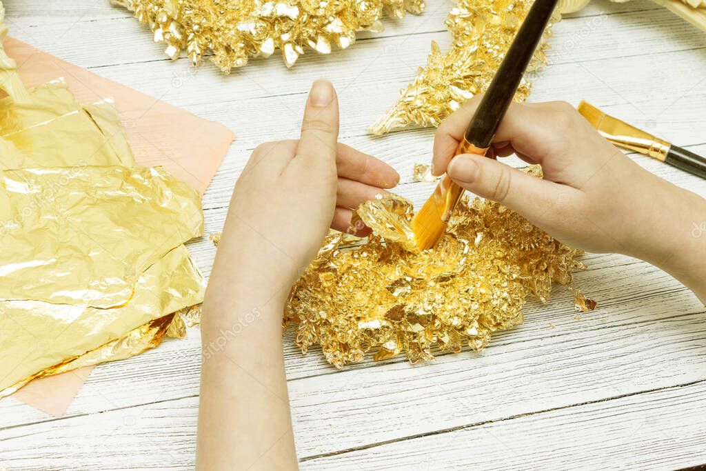 Gilding process. Female hands with a brush. Gold leaf