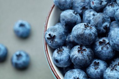 Koyu gri masa arkaplanındaki kasede taze seçilmiş yaban mersini.