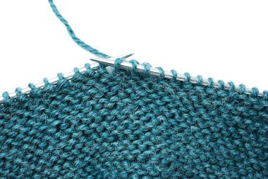 Örgü iğneleri ve örgü yün kumaşlar beyaz arka planda izole edilmiş. Çalışma devam ediyor