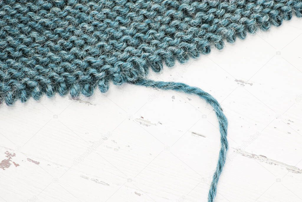 Unravelling knitted fabric on white background