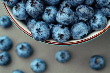 Koyu gri masa arkaplanındaki kasede taze seçilmiş yaban mersini.