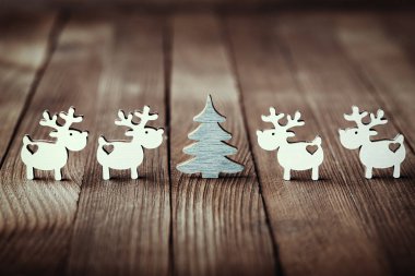 Beyaz ren geyikleri ve Noel ağaçlarının ahşap zemin üzerindeki kompozisyonu. Noel dekoru